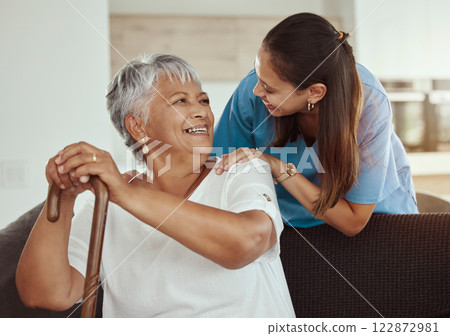 Happy, relax and senior woman with caregiver smile while sitting on a living room sofa in a nursing home. Support, help and professional nurse or healthcare worker helping elderly lady or patient 122872981
