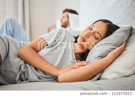 Sleeping, peace and woman asleep on bed with comfortable pillow while taking nap to relax with sleepless partner in background. Couple, sexual problems and carefree wife lying eyes closed next to man 122873023