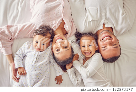 Portrait of family home, kids and parents on bed for fun morning, relax lifestyle and happiness. Above of smile mom, happy dad and playful children together in bedroom for love, care and joy weekend Portrait of family home, kids and parents on bed for fun morning, relax lifestyle and happiness. Above of smile mom, happy dad and playful children together in bedroom for love, care and joy weekend 122873177
