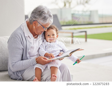 Senior woman, happy baby and children book reading of a grandmother spending quality time together. Elderly retirement of a old female about to read a fun kids story to a kid on a home patio 122873283