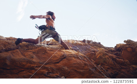 Mountain, sport and climbing with a sports man running along a rocky surface for health, fitness and exercise. Workout, training and cardio with a young male climber athlete in the mountains 122873591