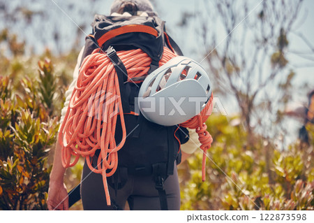 Sports, mountain and climbing with a person hiking and carrying equipment, rope and a helmet outdoor in nature. Adventure, sport and fitness with an adult on a climb, journey or hike in the forest 122873598