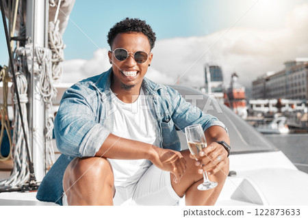 Happy, sea and man on a luxury yacht or catamaran enjoying a glass of champagne on a summer holiday alone. Lifestyle, smile and young person in sunglasses drinking wine on cruise boat to relax at sea 122873633
