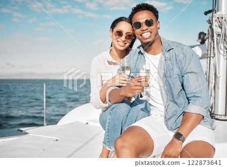 Happy couple on yacht with champagne smile and celebrate love with romantic tropical holiday travel on ocean. Dating man and woman on luxury boat on beach water or sea with wine glass for celebration 122873641