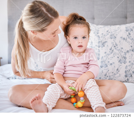 Portrait of girl with mother in bedroom in home, bonding and playing while holding toy. Love, family and caring happy woman with little kid, child or toddler spending free time together in the house 122873724