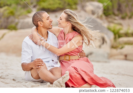 Love, hug and couple on the beach look into eyes and relax outdoor together on sand or ground. Happy interracial black man and woman enjoy summer holiday in nature for valentines day or anniversary 122874053