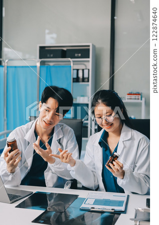 Positive doctor working on laptop in medical office, portrait. Positive doctor working on laptop in medical office, portrait. 122874640