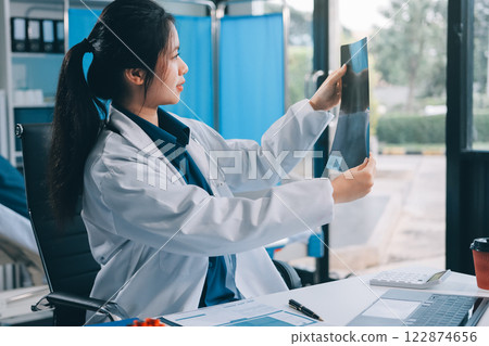 Positive doctor working on laptop in medical office, portrait. 122874656