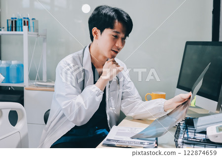Positive doctor working on laptop in medical office, portrait. Positive doctor working on laptop in medical office, portrait. 122874659