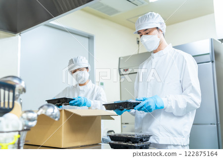 Cooking staff packing food into cardboard boxes, school lunch center, back yard Cooking staff packing food into cardboard boxes, school lunch center, back yard 122875164