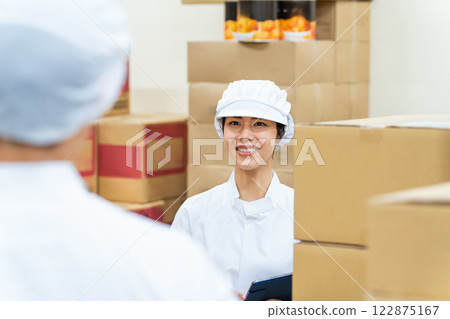A woman in a white coat working in a warehouse 122875167