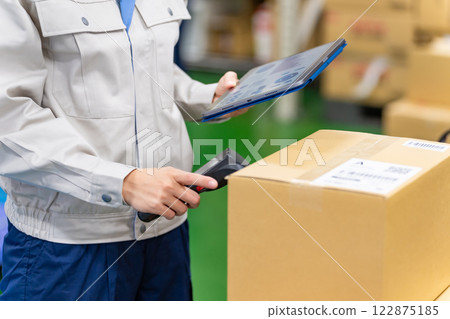A female worker scans and manages luggage labels with a barcode reader 122875185