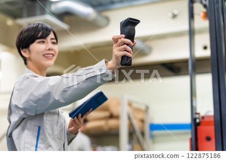 一名女員工在倉庫工作,手持手持終端機和平板電腦 一名女員工在倉庫工作,手持手持終端機和平板電腦 122875186