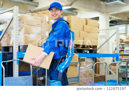 A worker using a power assist suit in a warehouse 122875197