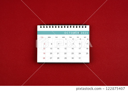 October 2025 desk calendar on red background in the middle. 122875407