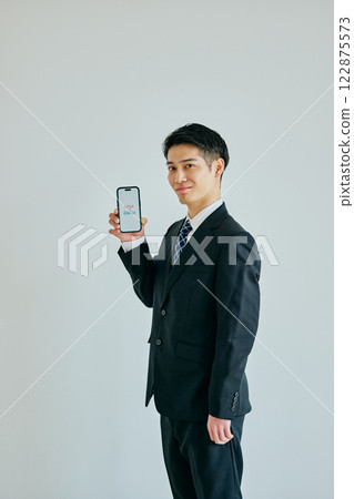 一名 20 多歲的年輕男子拿著智慧型手機 NISAvsiDeCo 122875573