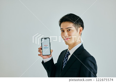 A young man in his 20s holding a smartphone NISAvsiDeCo 122875574