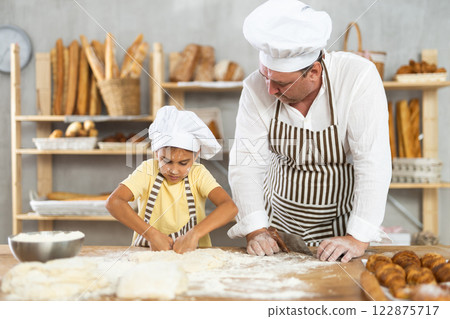 Father and daughter roll out dough together to make delicious bread 122875717