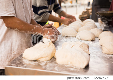 Male hands knead yeast dough for baking bread Male hands knead yeast dough for baking bread 122875750