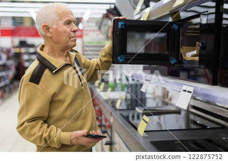 Senor man pensioner buying microwave oven in showroom of electrical appliance store Senor man pensioner buying microwave oven in showroom of electrical appliance store 122875752