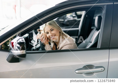 Happy business woman sitting in new car at dealership showroom Happy business woman sitting in new car at dealership showroom 122875840