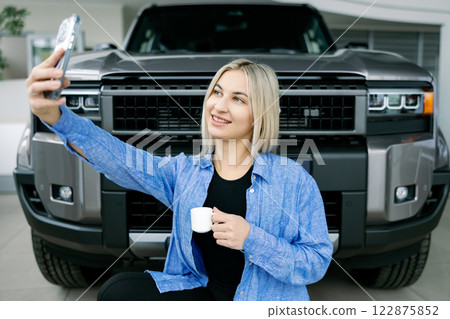 Woman taking selfie with new pickup truck while enjoying coffee Woman taking selfie with new pickup truck while enjoying coffee 122875852