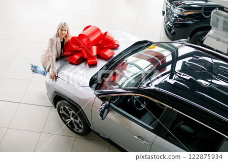Woman Leaning on New Car with Red Bow in Dealership 122875934