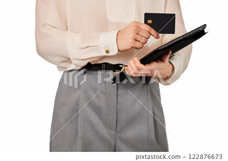 woman in white blouse and grey pants using credit card and digital tablet on white background 122876673