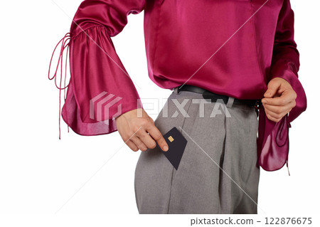 Caucasian female hand putting black premium credit bank card in pants pocket on white background. Money finance 122876675
