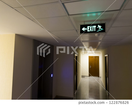 Sign on ceiling showing direction to emergency exits along stairs Sign on ceiling showing direction to emergency exits along stairs 122876826