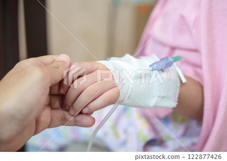 Mother holding child hand with saline IV solution in hospital Mother holding child hand with saline IV solution in hospital 122877426