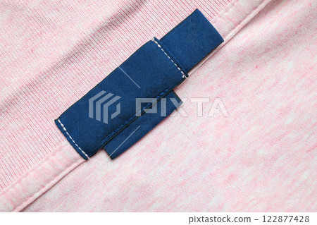 Blank blue laundry care clothes label on pink shirt fabric texture background Blank blue laundry care clothes label on pink shirt fabric texture background 122877428