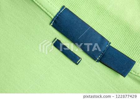 Blank blue laundry care clothes label on green shirt fabric texture background Blank blue laundry care clothes label on green shirt fabric texture background 122877429
