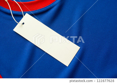 Blank white clothes tag label on blue fabric texture background 122877628