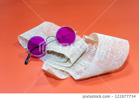 Purple round glasses on top of a brown teal with an orange background Purple round glasses on top of a brown teal with an orange background 122877734