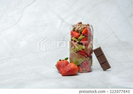 Trend Dubai chocolate strawberry cup with kunafa, pistachio paste, tahini, milk chocolate and fresh strawberries. Decorated with strawberries and chocolate bar piece. Copy space for text. 122877843