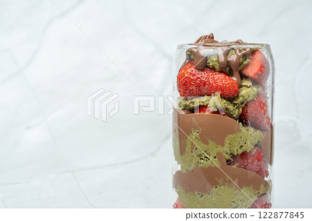 Close up of Dubai chocolate strawberry cup with kunafa, pistachio paste, tahini, chocolate and fresh strawberries. Copy space. Sweets and desserts, take away street food. 122877845