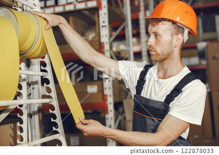 Industrial worker indoors in factory. Young technician with orange hard hat. Industrial worker indoors in factory. Young technician with orange hard hat. 122878033