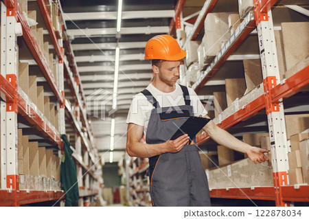 Industrial worker indoors in factory. Young technician with orange hard hat. Industrial worker indoors in factory. Young technician with orange hard hat. 122878034
