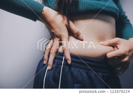 Asian Woman Pinching Her Belly Fat With Left Hand Asian Woman Pinching Her Belly Fat With Left Hand 122878224