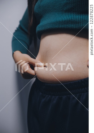 Asian Woman Pinching Her Belly Fat With Left Hand Asian Woman Pinching Her Belly Fat With Left Hand 122878225