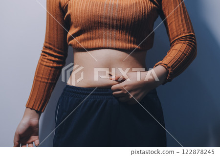 Asian Woman Pinching Her Belly Fat With Left Hand Asian Woman Pinching Her Belly Fat With Left Hand 122878245