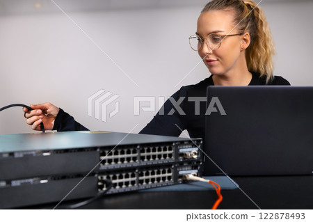 IT technician professional configuring network switch and managing network cables and hardware in a data center environment IT technician professional configuring network switch and managing network cables and hardware in a data center environment 122878493