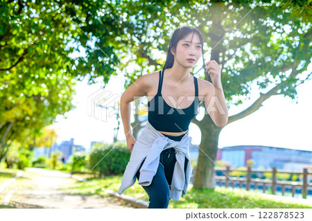 A cool woman jogging on a road with sunlight filtering through the trees, running, diet, exercise, exercise 122878523