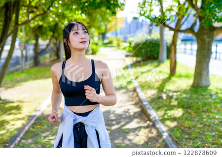A cool woman jogging on a road with sunlight filtering through the trees Walking Diet Exercise Exercise 122878609