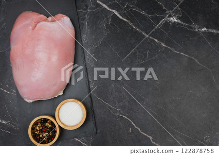 Close-up of raw turkey fillet lying on a black stone plank with spices and salt in wooden bowls side by side on a dark background with space for text. The concept of proper and healthy nutrition, diet Close-up of raw turkey fillet lying on a black stone plank with spices and salt in wooden bowls side by side on a dark background with space for text. The concept of proper and healthy nutrition, diet 122878758