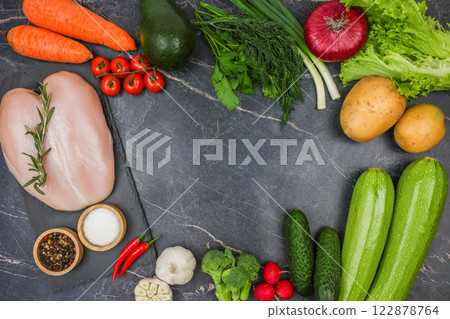 Raw meat, spices, vegetables and herbs lie around on a dark background with space for text. The concept of healthy and proper nutrition, natural products, dietary menu. High quality photo 122878764