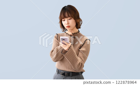 Woman/businesswoman thinking while looking at her smartphone Woman/businesswoman thinking while looking at her smartphone 122878964