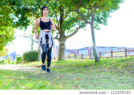 陽光透過樹叢灑在路上，一位酷酷的女士在路上慢跑 散步 節食 鍛煉 鍛煉 122879145