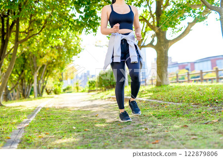 A cool woman jogging on a road with sunlight filtering through the trees Walking Diet Exercise Exercise A cool woman jogging on a road with sunlight filtering through the trees Walking Diet Exercise Exercise 122879806